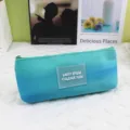 Close-up of tie-dye pencil case with gradient blue fabric and clear logo patch - Blue