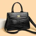 Elegant black crocodile-embossed handbag with gold flower lock and shoulder strap - Black
