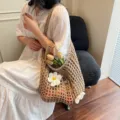 Elegante bolso tote de malla de ganchillo beige con flores blancas y fondo de madera - Caqui