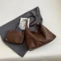 Juego de bolsos hobo vintage marrón con una pequeña bolsa a juego sobre un blazer gris - Café