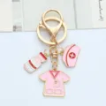 Close-up of pink nurse-themed metal keychain with hat and scrub charms - Pink