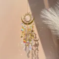 Dettaglio dell'acchiappasole in cristallo a forma di sole e luna con riflessi arcobaleno - Luna di fuoco dorata