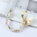 Detailweergave van een elegante polsband voor telefoon van parels en zijden sjaal met gouden sluiting - Beige Bloemenstijl (K176-6)