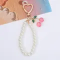 Close-up view of a sweet pearl phone strap featuring pink cherry charms and a gold heart clasp. - Gold Pink Cherry