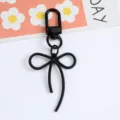 Macro detail of a minimalist black alloy bow keychain with a matching lobster clasp - Black