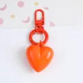 Macro view of a vibrant orange heart-shaped resin keychain with matching metal hardware clip - Orange