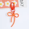 Close-up detail of the vibrant orange alloy bow keychain with a secure lobster clasp hook - Orange