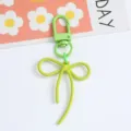 Macro detail of a lime green alloy bow-shaped keychain featuring a matte textured finish - Light Green