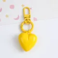 Close-up of a vibrant yellow candy-colored resin heart keychain with matching hardware. - Yellow