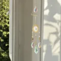 Vista dettagliata dell'acchiappasogni con cristalli iridescenti e ciondoli dorati - Stile sole triangolare