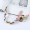 Macrodetail van de elegante parel- en zijden sjaal telefoonarmband met gouden sluitingen - Veelkleurige Printstijl (K176-15)