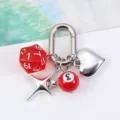 Close-up of multi-sided dice keychain with heart, star and billiard ball charms - Red