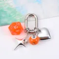 Close-up detail of a silver keychain featuring orange dice and billiard ball charms - Orange