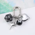 Detailed close-up of metallic keychain charms featuring a black dice, 8-ball, heart, and star. - Black
