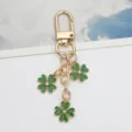 Close-up of a gold-tone keychain featuring three green shamrock charms with crystal centers. - Dark Green