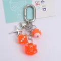 Detailed macro shot of bright orange lucky dice and heart charms on a silver keychain - Orange