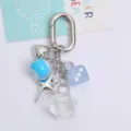Macro detail of Y2K style silver keychain featuring blue eye, dice, and star charms - Blue