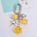Macro view of creative keychain featuring yellow dice, silver heart and star charms - Yellow