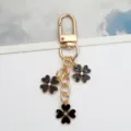 Elegant black enamel four-leaf clover keychain with gold alloy finish and crystal centers - Black