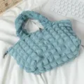 Detalle de un bolso de mano azul claro con textura de burbujas plisadas sobre fondo blanco - Aguamarina