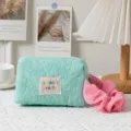 Detailed view of a mint green quilted floral makeup bag with a pink hair scrunchie - Light Green