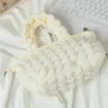 Vista detallada de un bolso de mano crema con textura de burbujas sobre fondo de tela - Blanco Roto