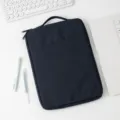 Minimalistische dunkelblaue Laptophülle auf weißem Schreibtisch mit Zubehör - Marineblau