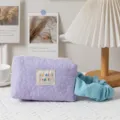 Close-up of lavender quilted floral cosmetic bag with embroidered label and blue scrunchie - Light Purple