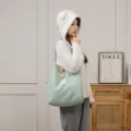Asiatisches Model mit einer großen, flauschig gestrickten Tragetasche in gemütlicher häuslicher Umgebung - Blau
