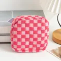 Detaillierte Makroansicht einer rosa karierten gestrickten Kosmetiktasche auf Schreibtisch - Rot