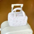 Elegante geblümte weiße PU-Reisekosmetiktasche mit drei Ebenen auf einem Koffer - Blumen Schleife