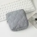 Detail der grauen gesteppten Kosmetiktasche mit Reißverschluss auf weißem Schreibtisch - 12.5*12.5*5cm / Grau