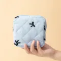 Detailopname van lichtblauwe gewatteerde opbergtas met zwart geborduurd strikje - 12.5*5*12.5cm / Lichtblauw