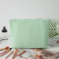 Detailansicht der grünen Seersucker-Kosmetiktasche mit Streifen in einer Lifestyle-Umgebung. - Grüne Streifen