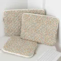 Detailed macro view of three quilted floral laptop sleeves set on a clean white desk - 11" / Yellow Floral