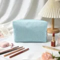Detailansicht einer blau-weiß gestreiften Seersucker-Kosmetiktasche mit Schönheitszubehör. - 16*9*9cm / Mintgrün