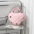 Nahaufnahme einer rosa gesteppten herzförmigen Handtasche mit schwarzer Schleifenstickerei - Rosa Stoff mit Bestickter Schleife