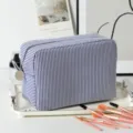 Close-up view of a blue and white striped seersucker makeup bag with pink brushes. - 22*9*15cm / Navy Blue