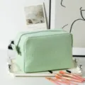 Detailed macro view of a green striped seersucker makeup bag in a lifestyle scene. - 22*9*15cm / Green Stripes
