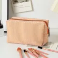 Detail der orange gestreiften Seersucker-Kosmetiktasche mit Pinseln auf weißem Grund - Clutch mit großer Kapazität / Orangene Streifen