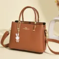 Elegant brown leather handbag for women featuring a cute white rabbit charm and gold hardware - Tan