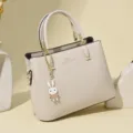 Elegant cream faux leather handbag with cute rabbit charm and golden kangaroo logo - Off White