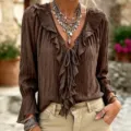 Close-up detail of the brown ruffled V-neck long sleeve blouse with elegant tie and pleats. - Dark Brown