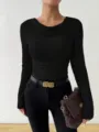 Close-up view of a black ribbed long sleeve knitted sweater worn by a stylish model. - S / Black