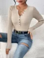Detailopname van een chique beige geribbelde gebreide top met knopen en lange mouwen. - XS / Abrikoos