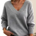 Close-up view of women's grey V-neck knitted sweater detail showing ribbed collar and cuffs. - S / Tops / Light Gray