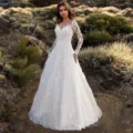 Detailed view of the elegant long-sleeve off-shoulder lace wedding dress in outdoor style. - S / Dresses / White
