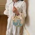 Woven straw bucket bag with blue 'hello' embroidery and floral scarf handle - Blue