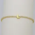 Detailed shot of a gold tennis bracelet featuring sparkling zircon stones and a cute puffy letter L charm. - Letter L (DB260303-L)