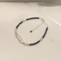 Elegante pulsera de perlas blancas y negras con accesorios de plata y cadena ajustable. - Pulsera